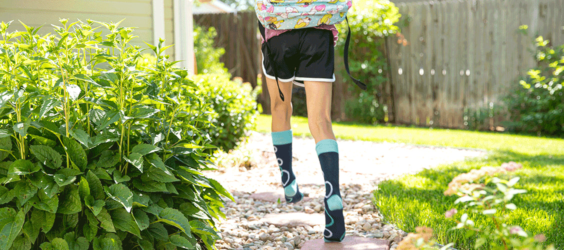 Young girl running in the yard with blue bubble socks and a backpack - How Kids Can Express Themselves During Back-to-School Shopping