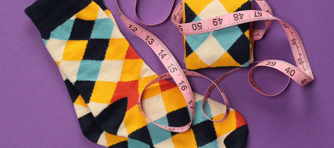 Colorful checker socks laying flat with measuring tape wrapped around them - How to Tell if Your Socks Fit
