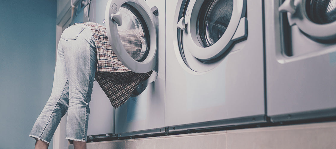 Woman at laundromat looking in washing machine - 8 Places to Find a Lost Sock