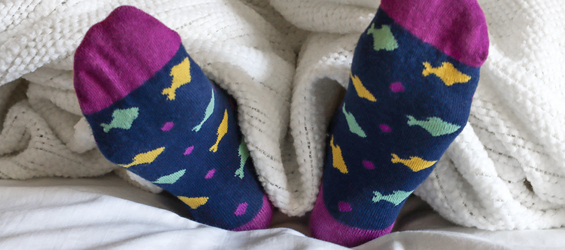 Feet with socks on sticking out of bed sheets - Sleeping with Socks On