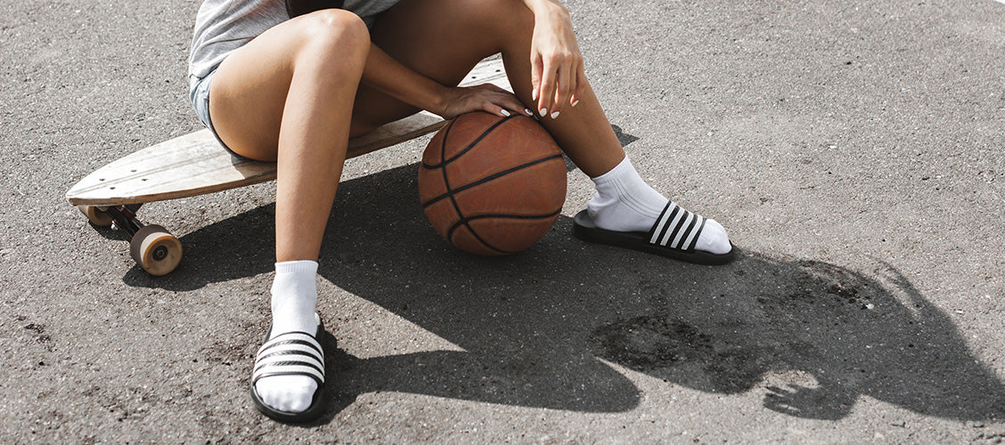 Young woman sitting on skateboard wearing quarter socks and sandals - Types of Socks