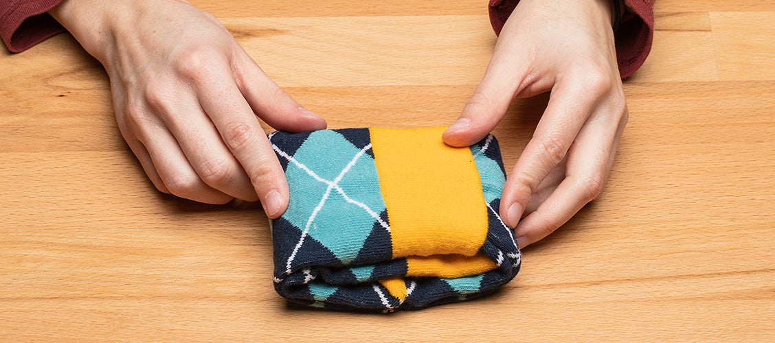 Hands folding argyle socks using the fold and tuck method