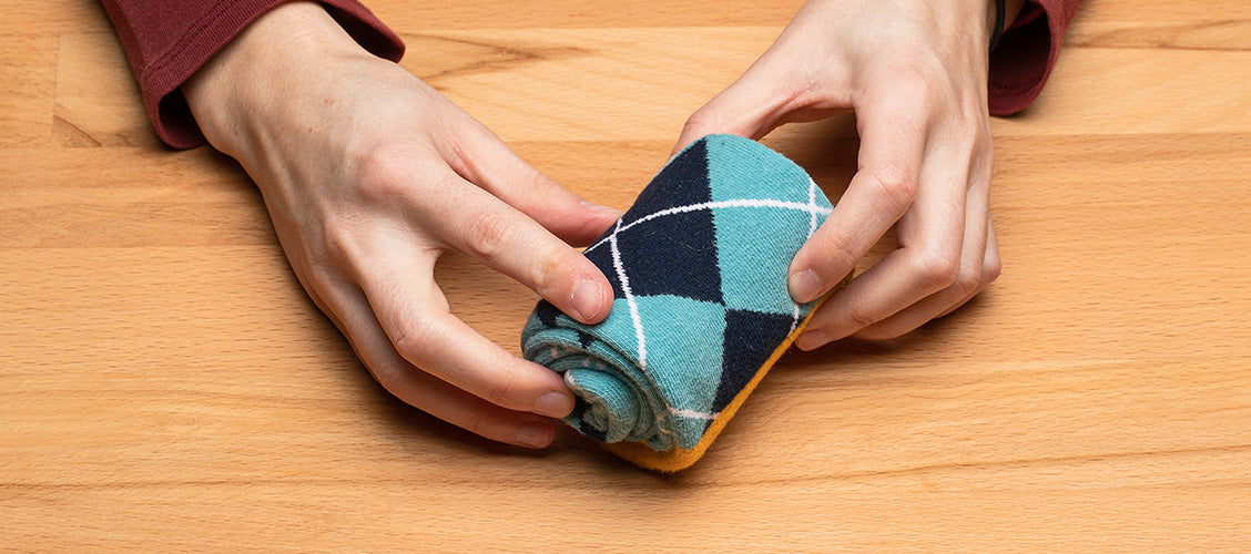 Hands folding argyle socks using the roll method