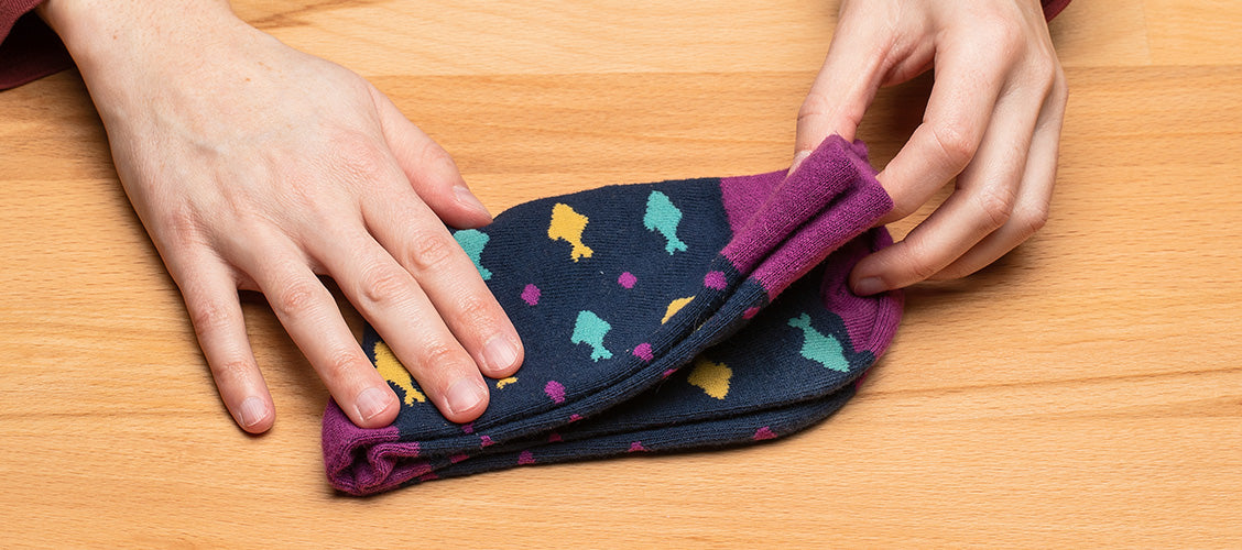 Hands folding fish socks using the single-fold method