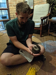 A man holding a wild hedgehog while sitting on porch