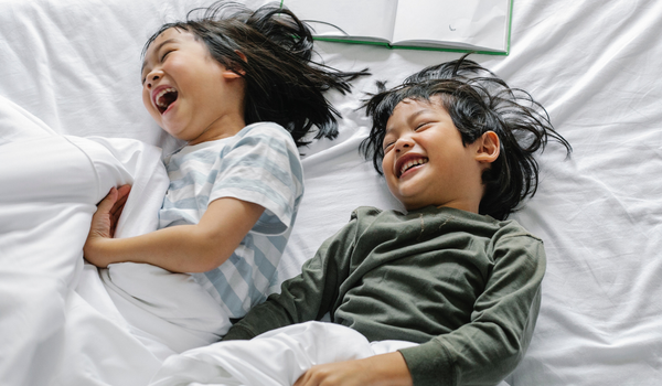 Young siblings giggling in bed together