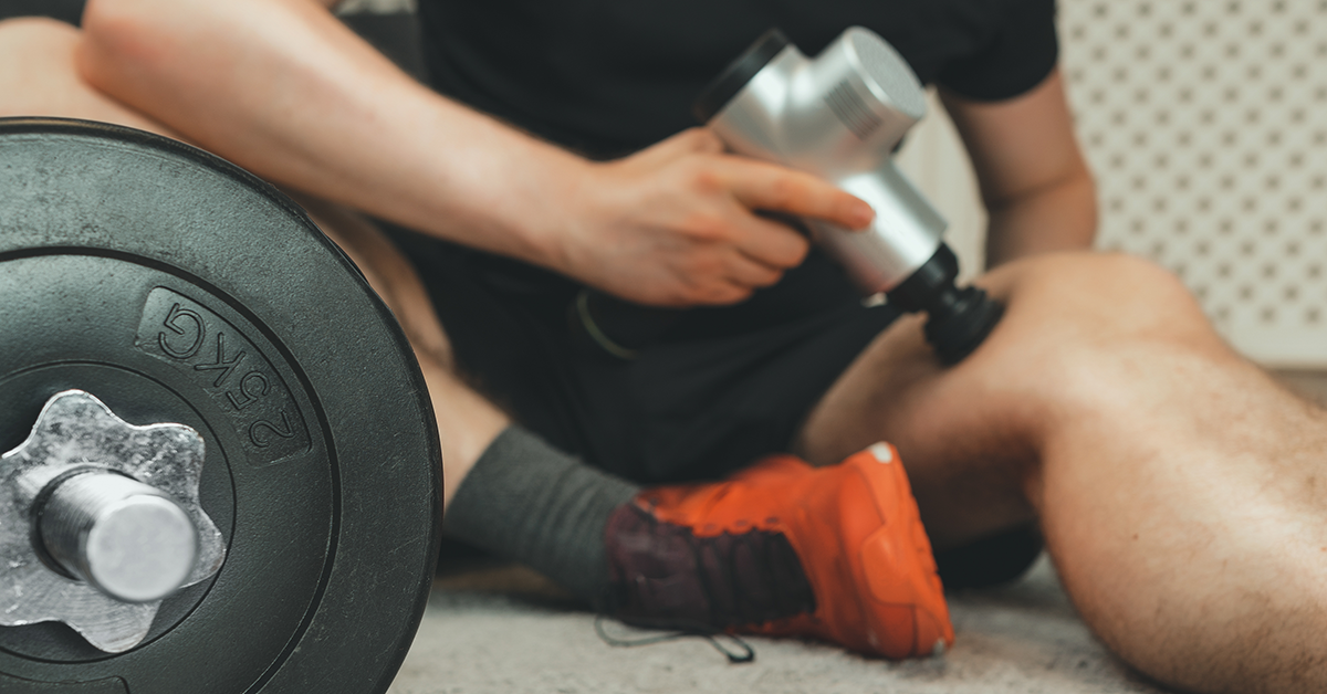 Guy using a massage gun on his leg