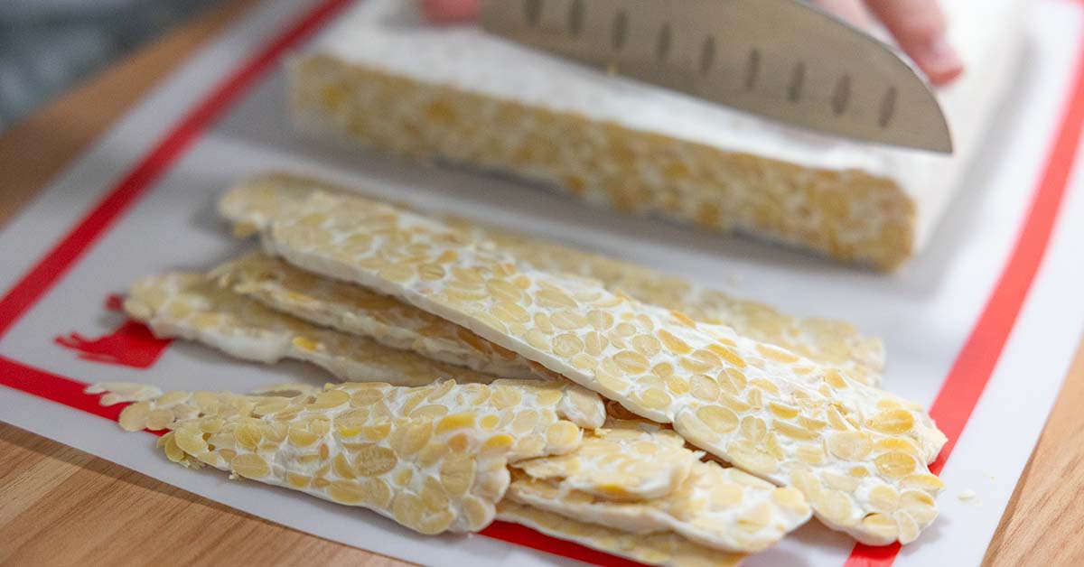 tempeh being cut into bacon slices