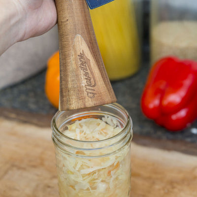 Sauerkraut in a Glass Container Pounded with Wooden Tool