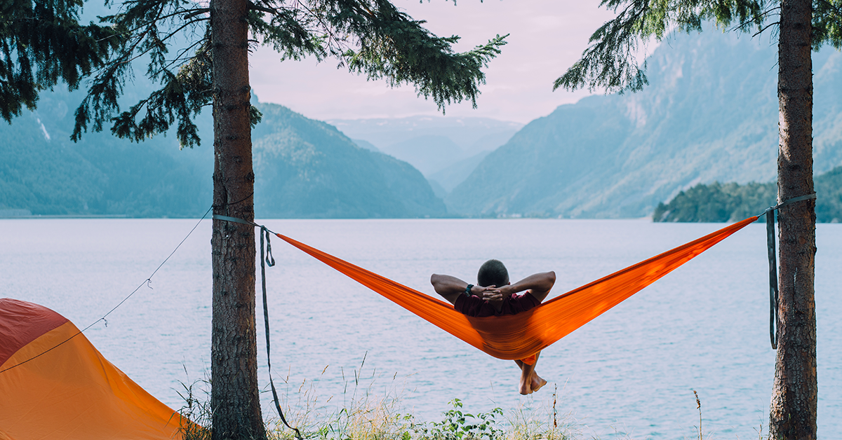 Guy hanging out in a portable hammock over a lake