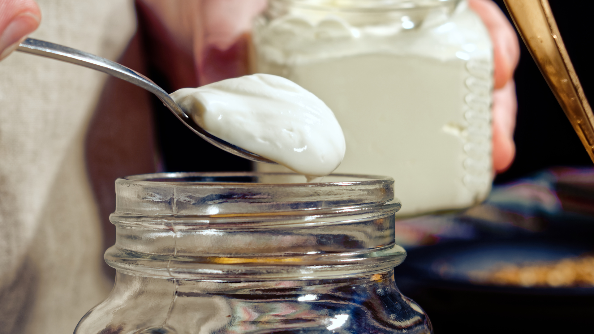 spooning homemade sour cream into a jar