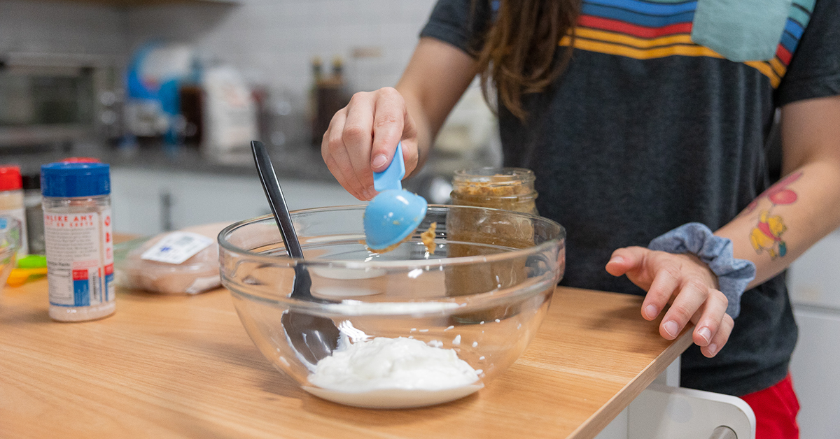 adding ingredients to yogurt marinade for chicken