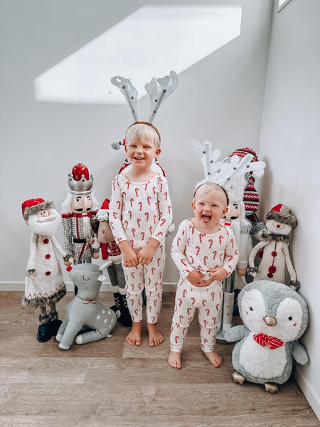 Spencer and Sienna pose in matching Christmas pajamas and reindeer antlers in front of Christmas decorations.