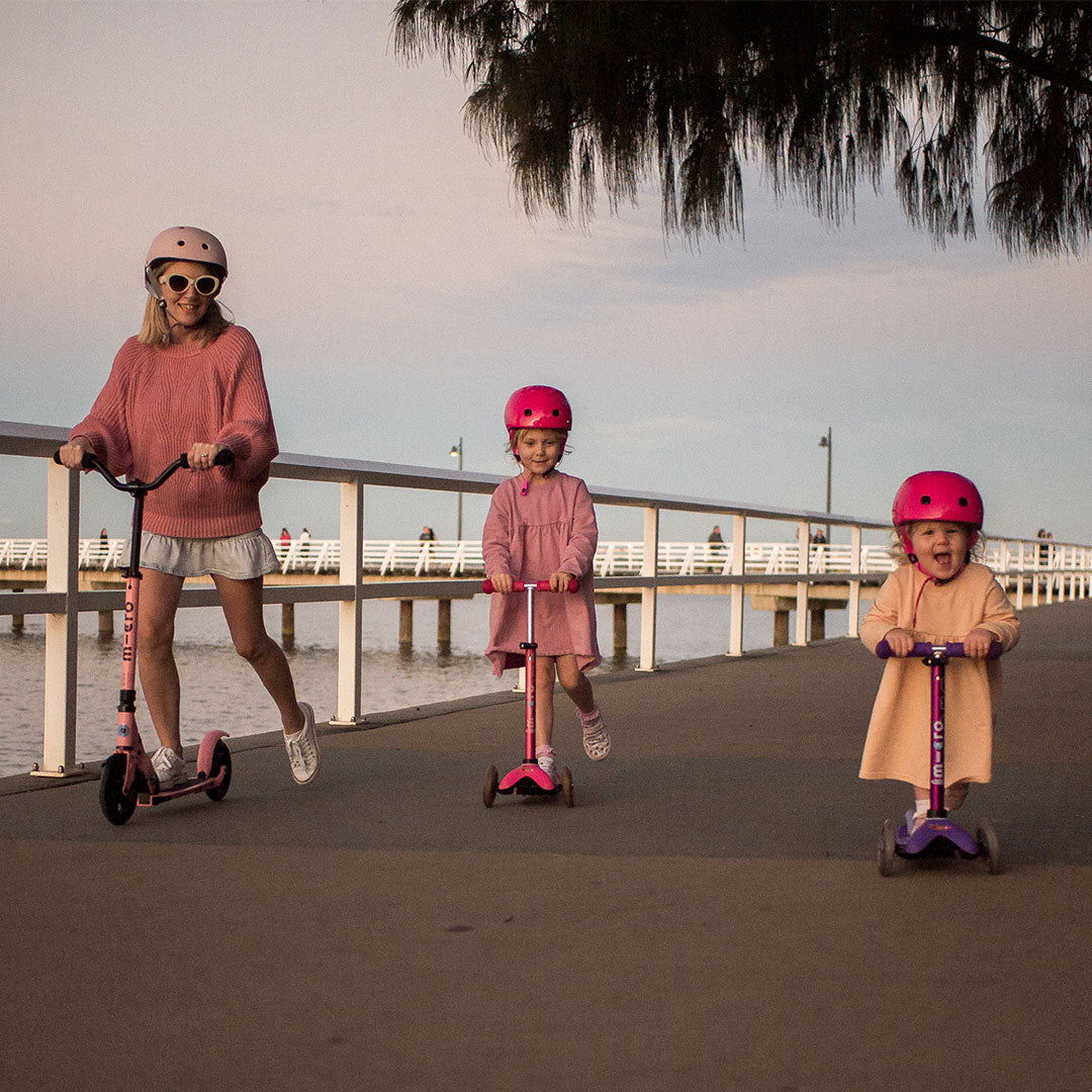 mum and children scooting along the water front