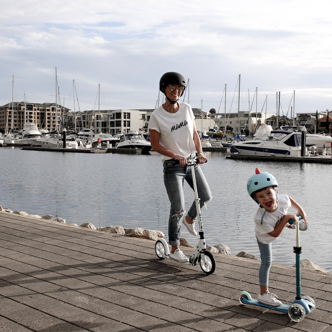 mother and son having fun riding their scooters along the waterfront