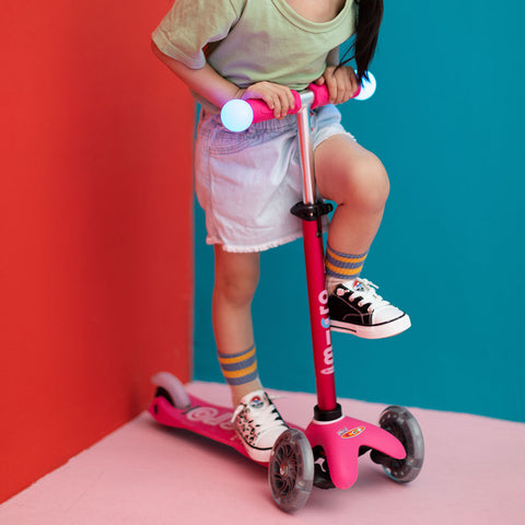 Toddler balancing on light up 3 wheel scooter