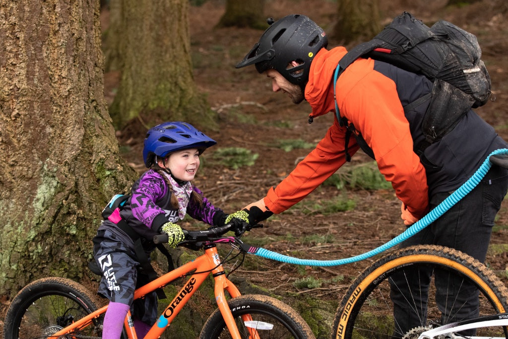Girl mountain biking with dad wearing bike gloves