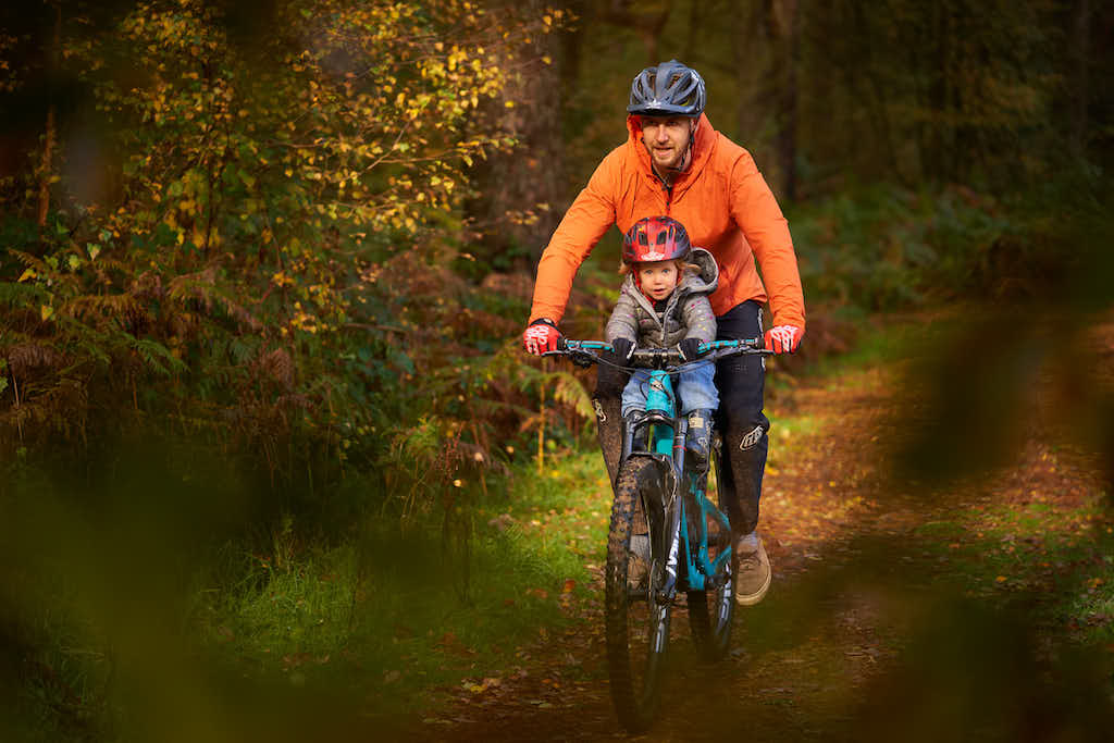 Kid mountain biking with dad on a shotgun kids bike seat