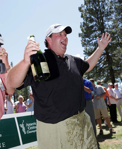 Brian Baumgartner holding a champagne bottle at an American Century Championship golf tournament