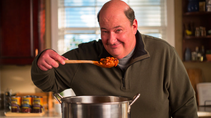 Brian Baumgartner holding a ladle with some Bush Beans chili sauce