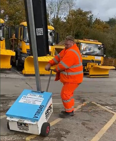 Highways man wrestling a portable traffic light with out Safety Handles