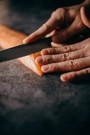 Person slicing salmon with Japanese knife