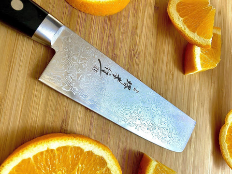 Sakai Takayuki Mirror Damascus Nakiri knife with oranges on cutting board.