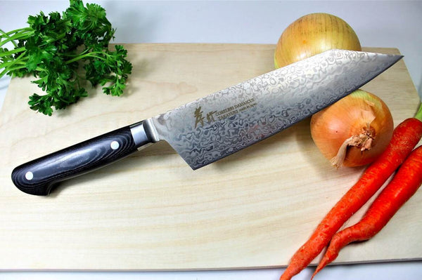 Steel Japanese Knife With Black Handle and Vegetables on Chopping Board