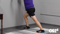 Man standing using wall to stretch calf