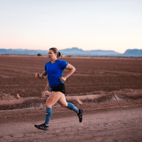 Woman running in desert with compression calf sleeves