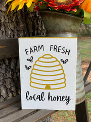 Farm Fresh Local Honey is shown sitting on a ladder with a rustic pitcher full of flowers.
