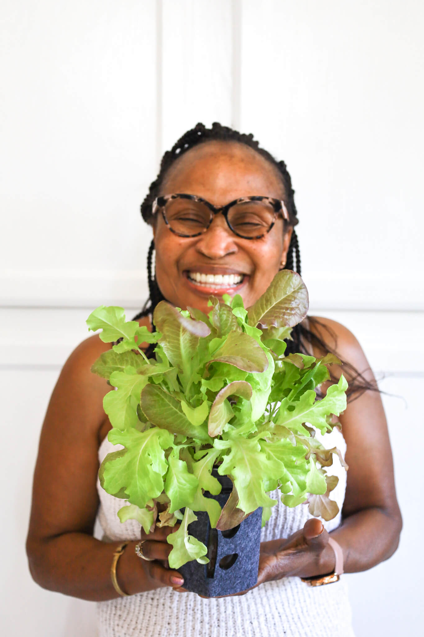 smiling woman holding lettuce grown indoors