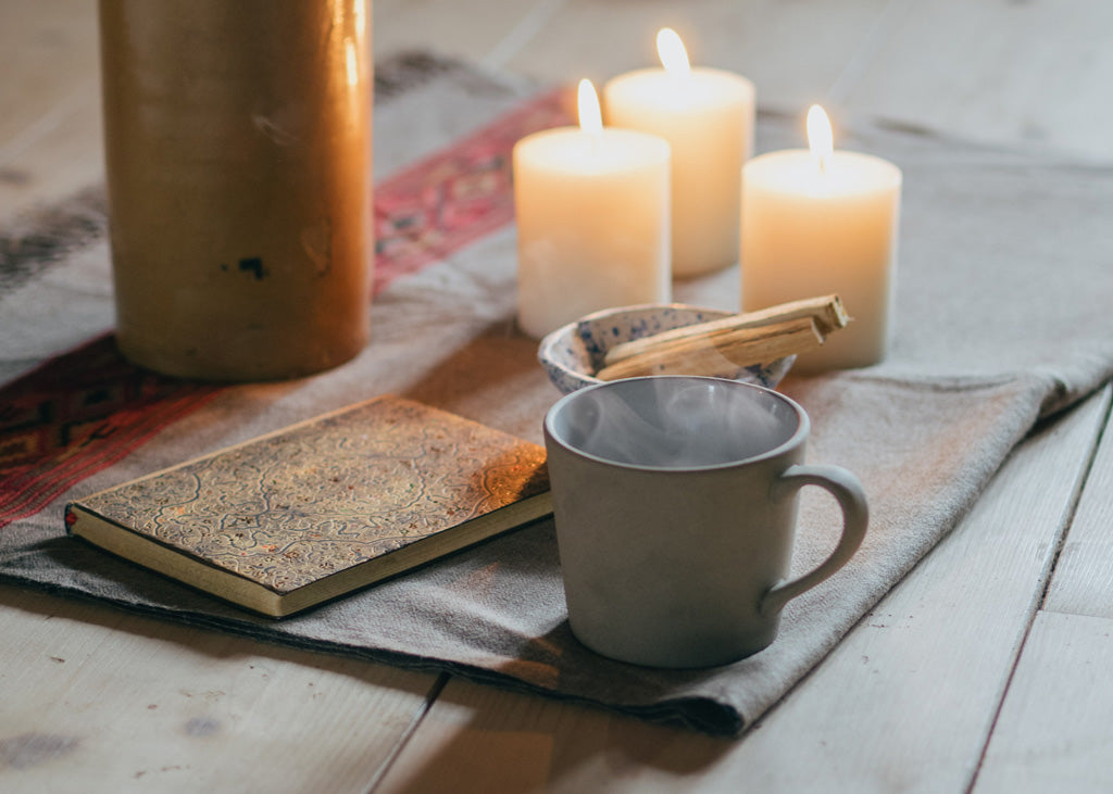 Rauhnächte: Teppich mit Journal, einer Tasse Tee und Kerzen