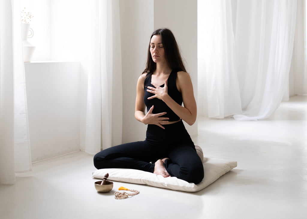 Woman sits on meditation cushion and meditates