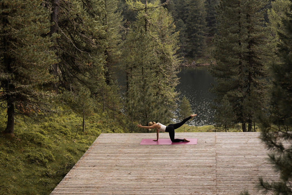 Frau praktiziert Yoga auf einem Steg