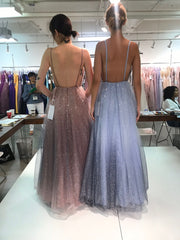 two models standing with their backs to us to show us the low back detail on their gowns.