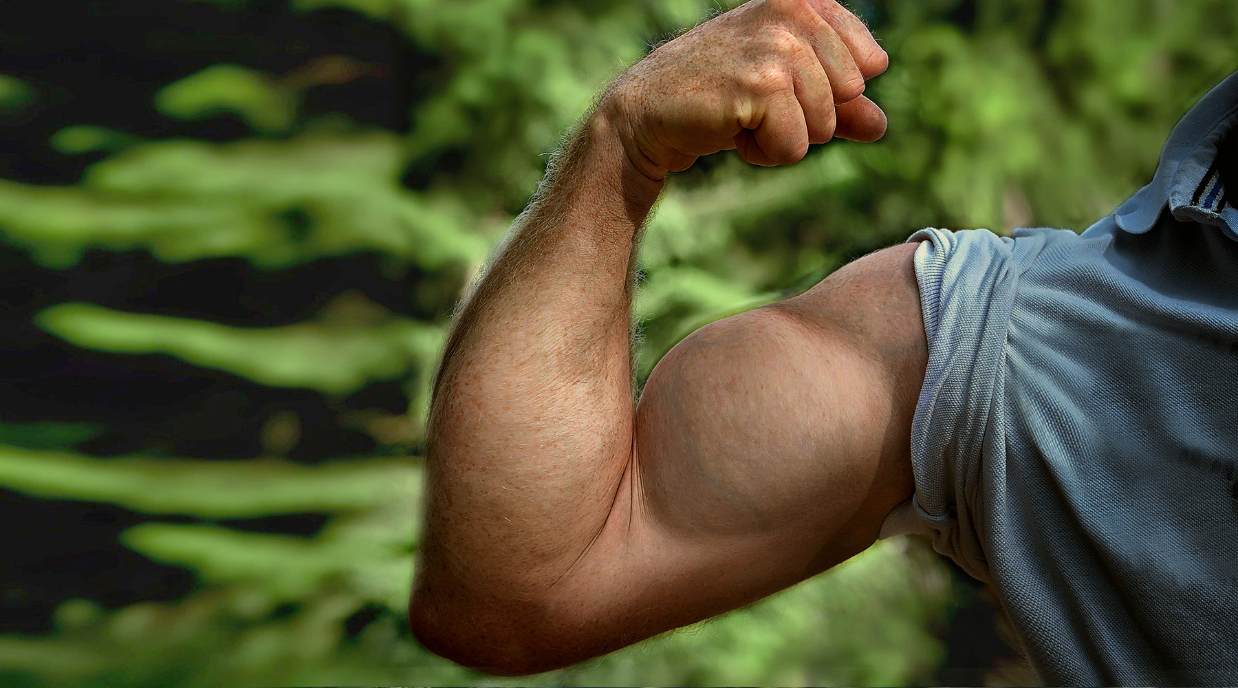 Hombre flexionando bíceps con un brazo muy fuerte, mostrando sólo el hombro y el brazo