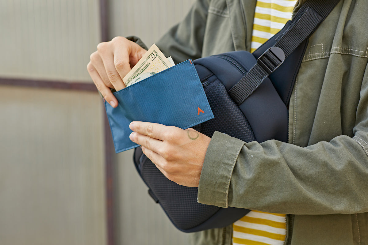 Man putting an Allett Wallet in bag