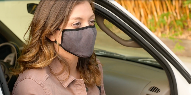 Frau mit Allett-Gesichtsmaske steigt aus ihrem Auto
