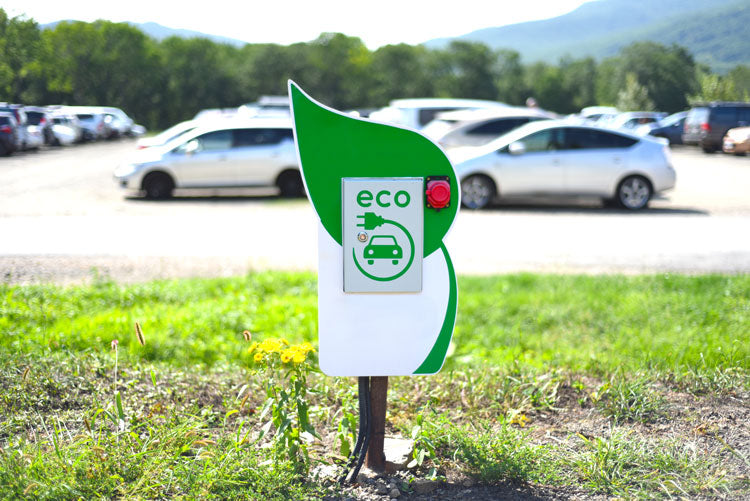 Eco sign in front of a parking lot full of electronic cars.