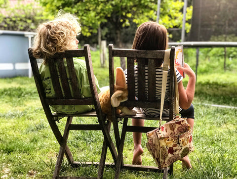 Two kids sitting on chair outside reading