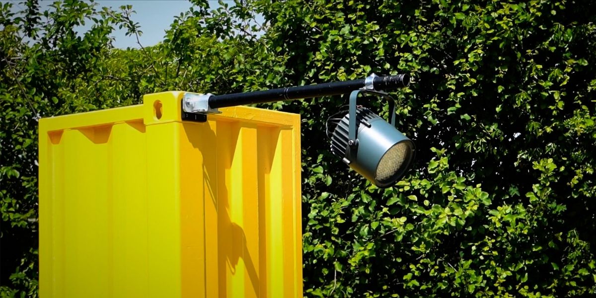A horizontal perpendicular tube attached to a shipping container with a light hanging from it