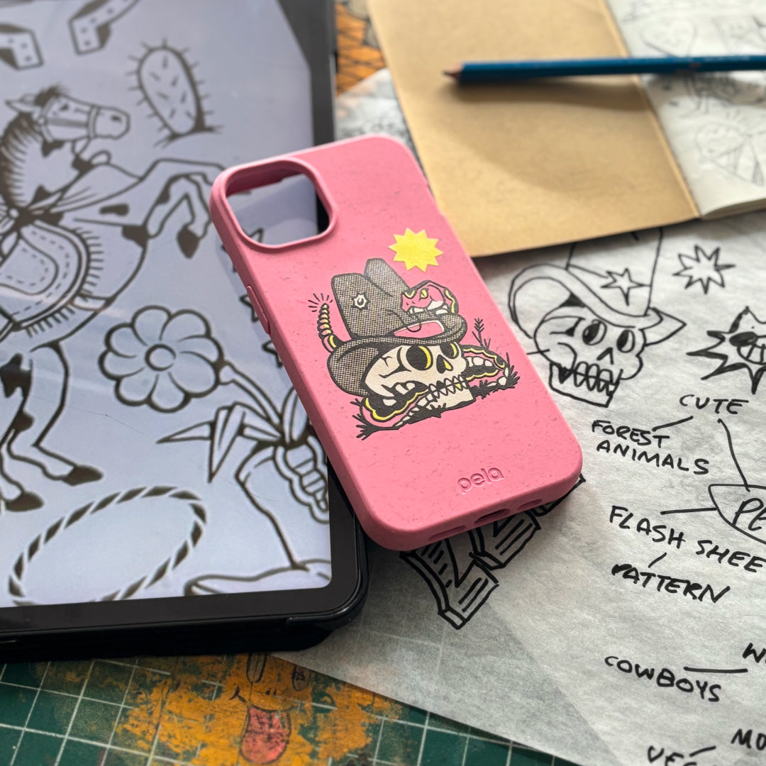 A pink phone case with a cartoon design on it, amidst artist sketches and drawing tools.