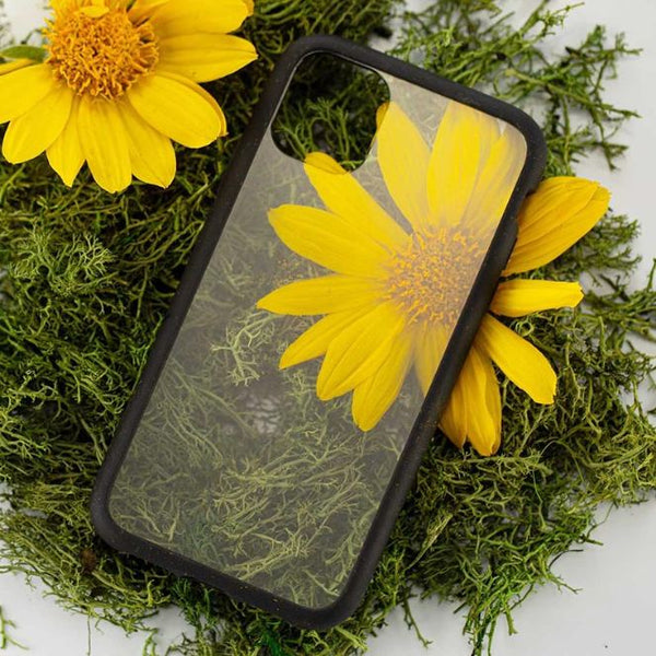A clear phone case sitting on a bed of flowers