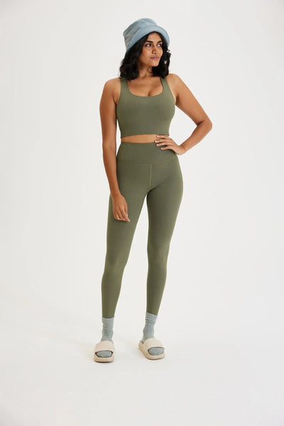 Dark haired woman wearing earthy green cotton leggings