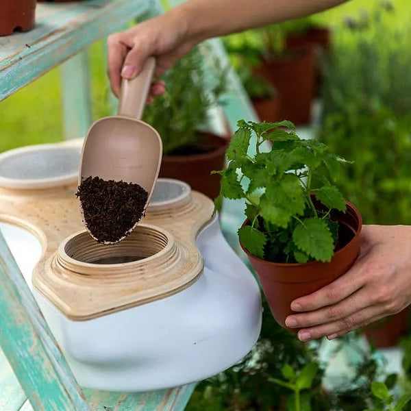 Hand scooping dirt into eco friendly living composter