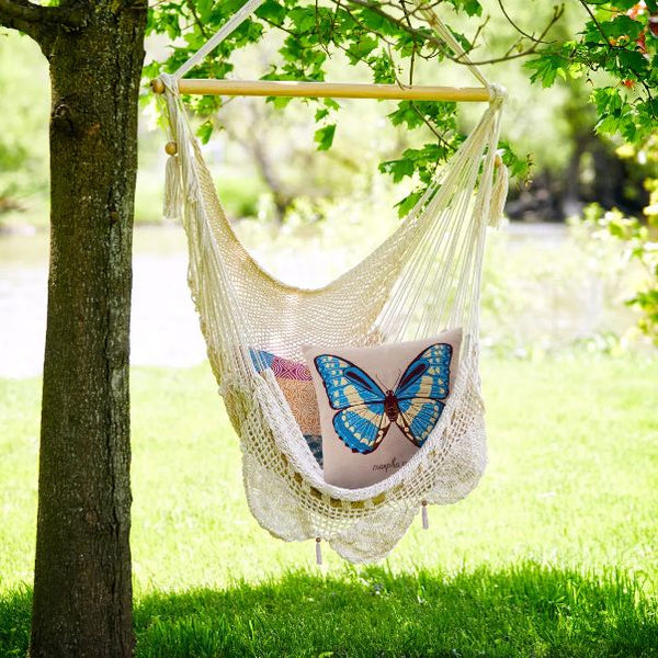 A cotton hammock swing outdoors by a tree