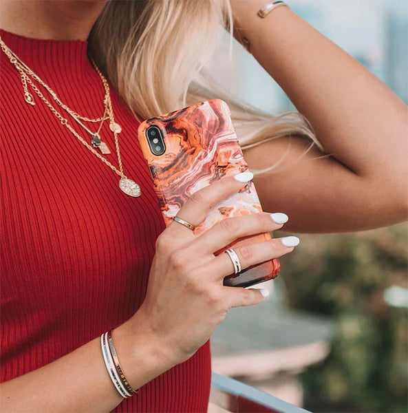 A woman in a red shirt holding an orange marble phone case