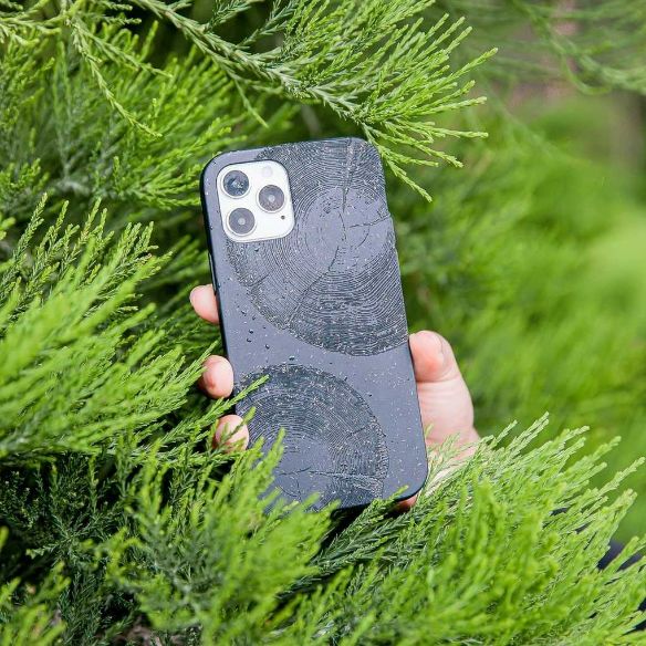 A black phone case with tree rings on a background of grass