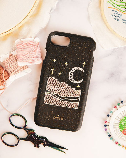 A black phone case with an outdoor scene stitched on the back